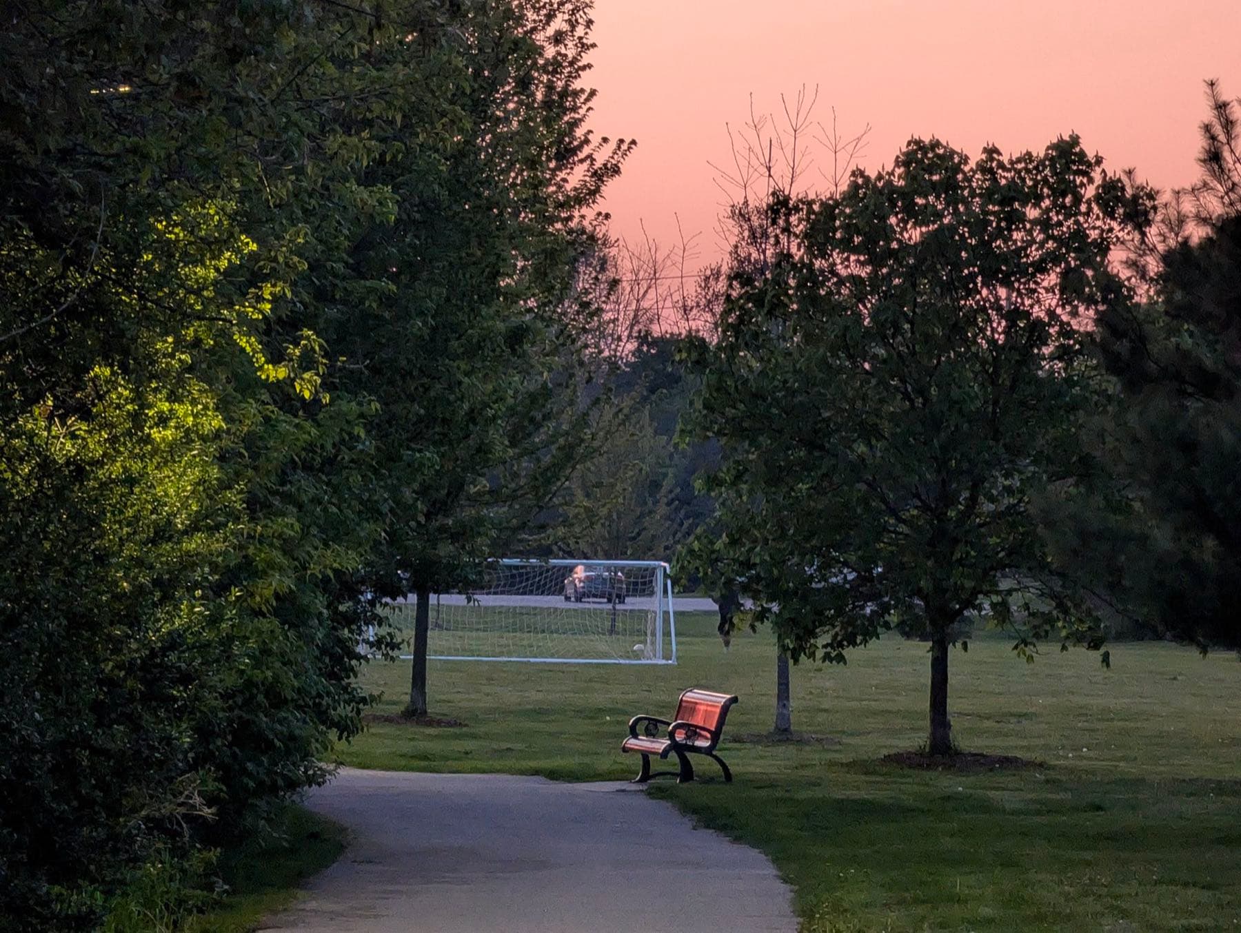A path through Centennial Park at sunset, with people on a bench under the trees
