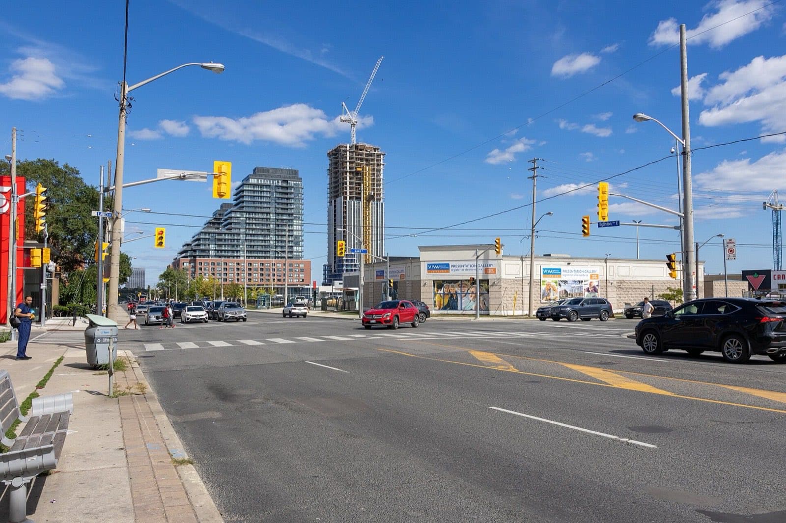 A wide intersection with shops on one side and new building work on the other
