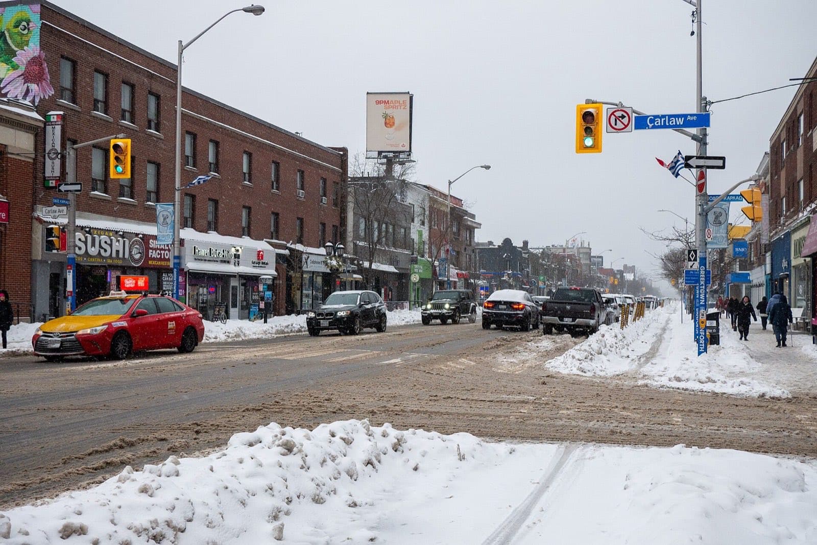 Shops along a main street in winter, with snow at the kerb
